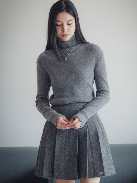 Woman in gray turtleneck sweater with skirt